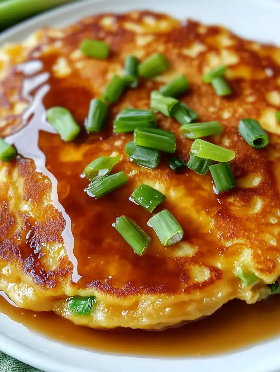 A close-up of a golden-brown pancake topped with chopped green onions and drizzled with a sweet sauce.