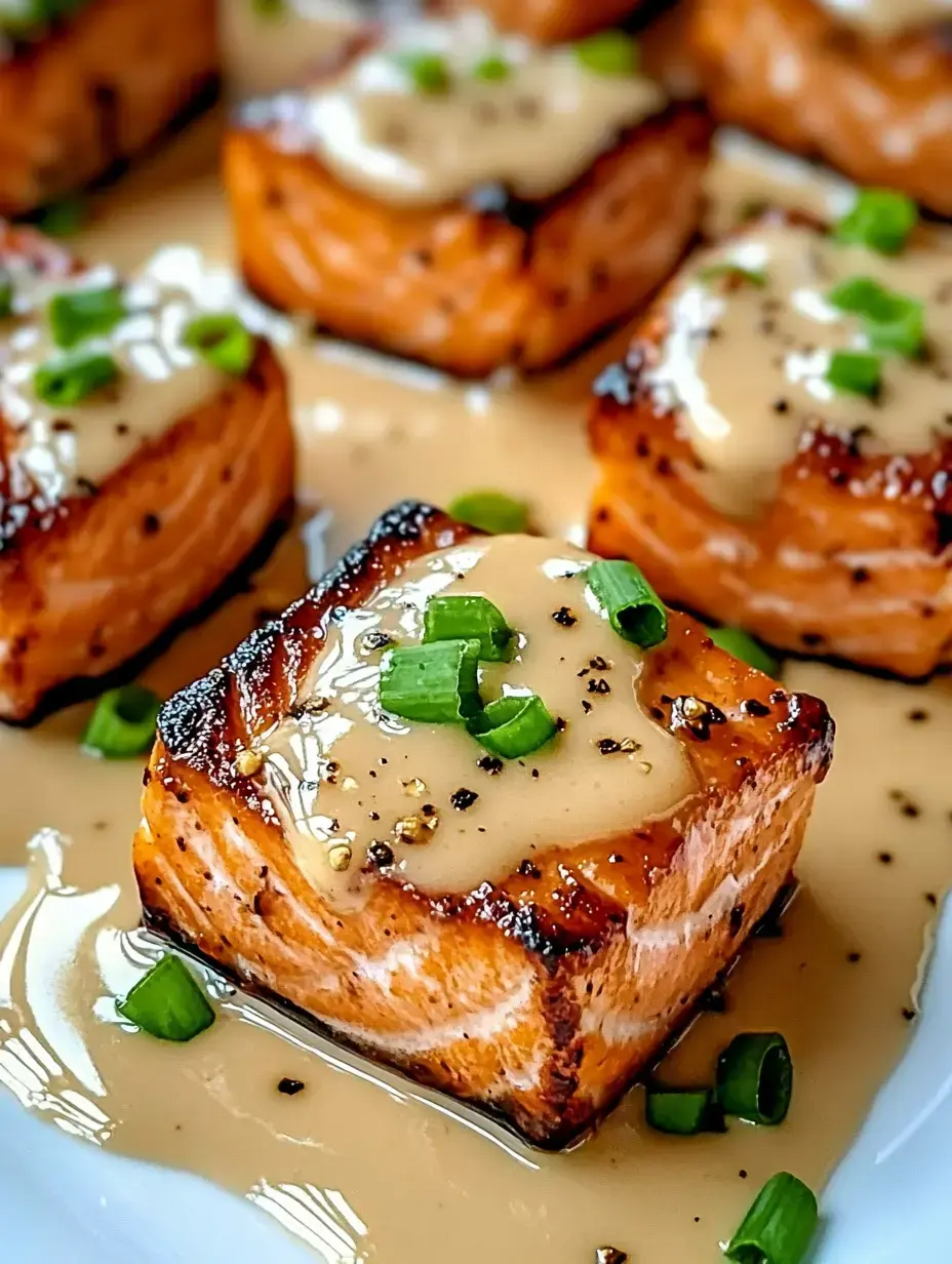 A zoomed-in view of sizzling salmon pieces topped with rich sauce and fresh green onion pieces.