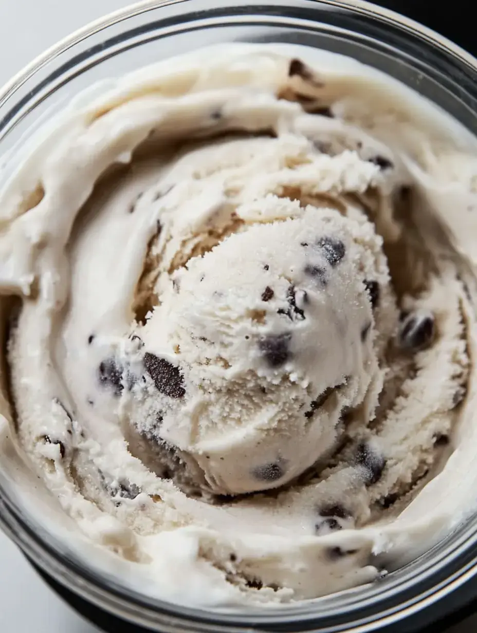 A close-up view of a container of ice cream with chocolate chip pieces swirled throughout.